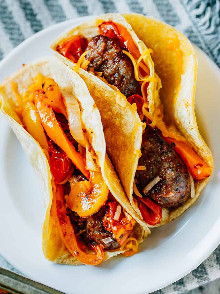 Flavorful sheet pan sausage and peppers in a street taco with melted cheese for the perfect fresh tasting tacos!