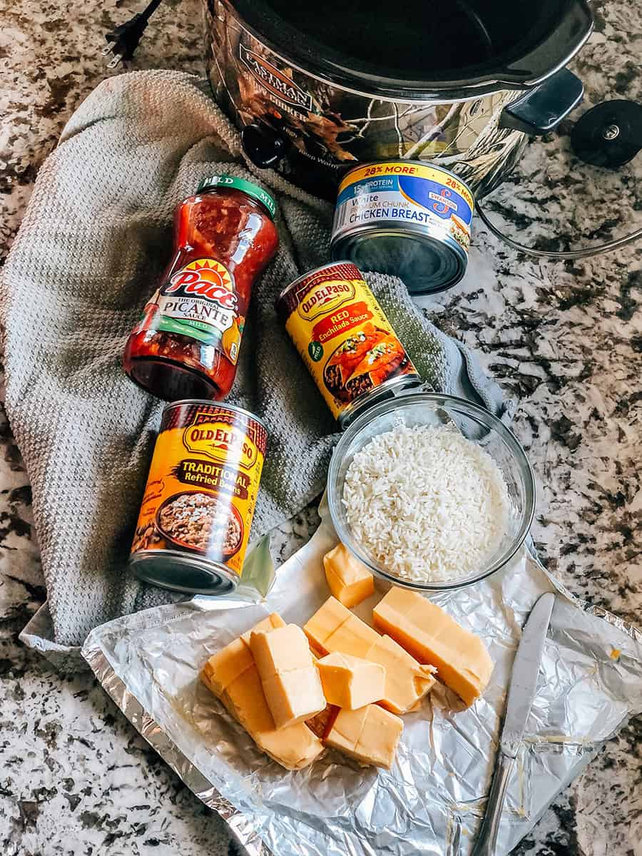 Vue d'ensemble de la recette de jambalaya au poulet : poitrine de poulet, riz, sauce enchilada rouge, salsa, haricots frits et fromage velveeta.