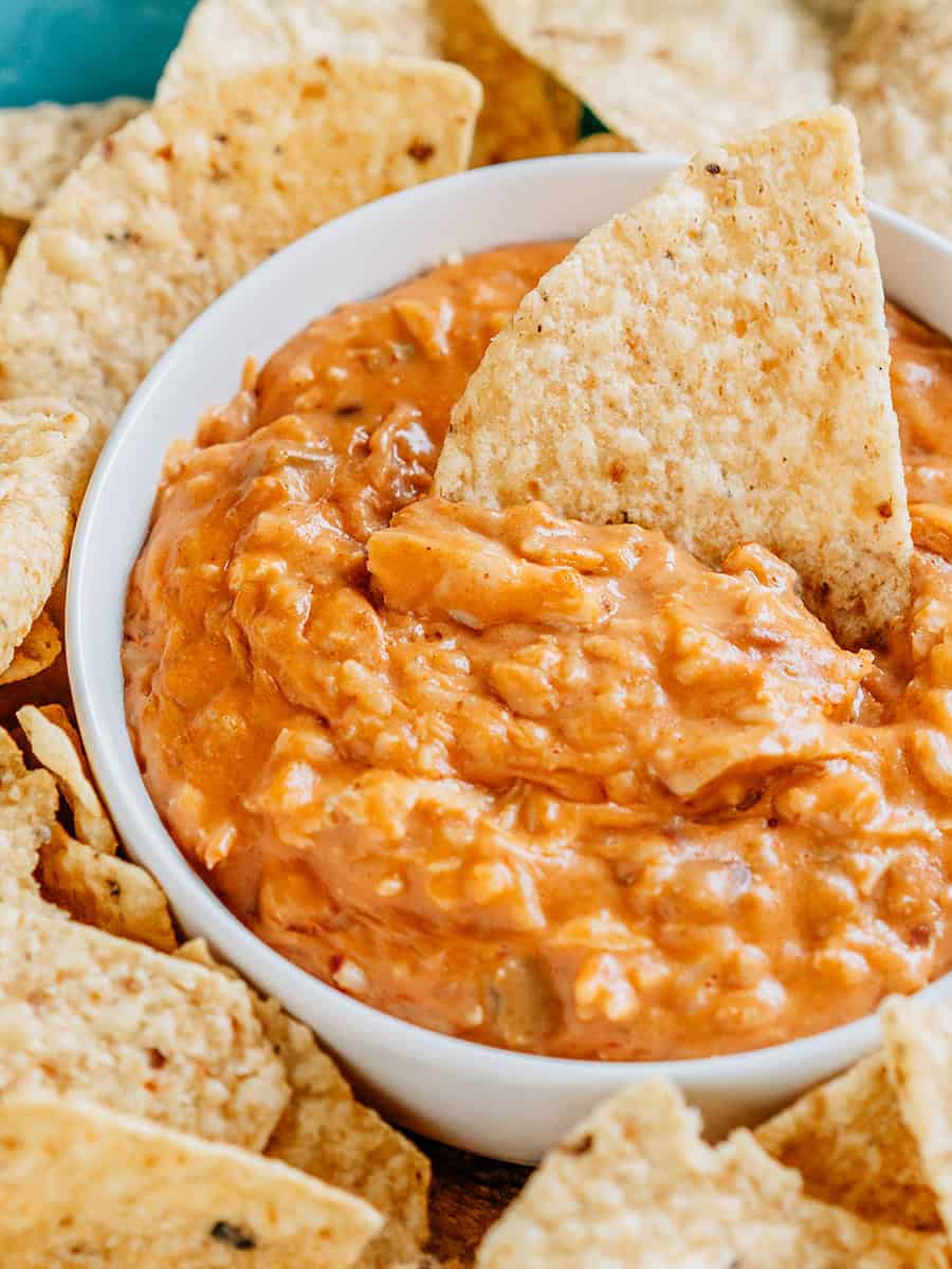 Une chips dans un bol de jambalaya au poulet entouré de chips tortilla.