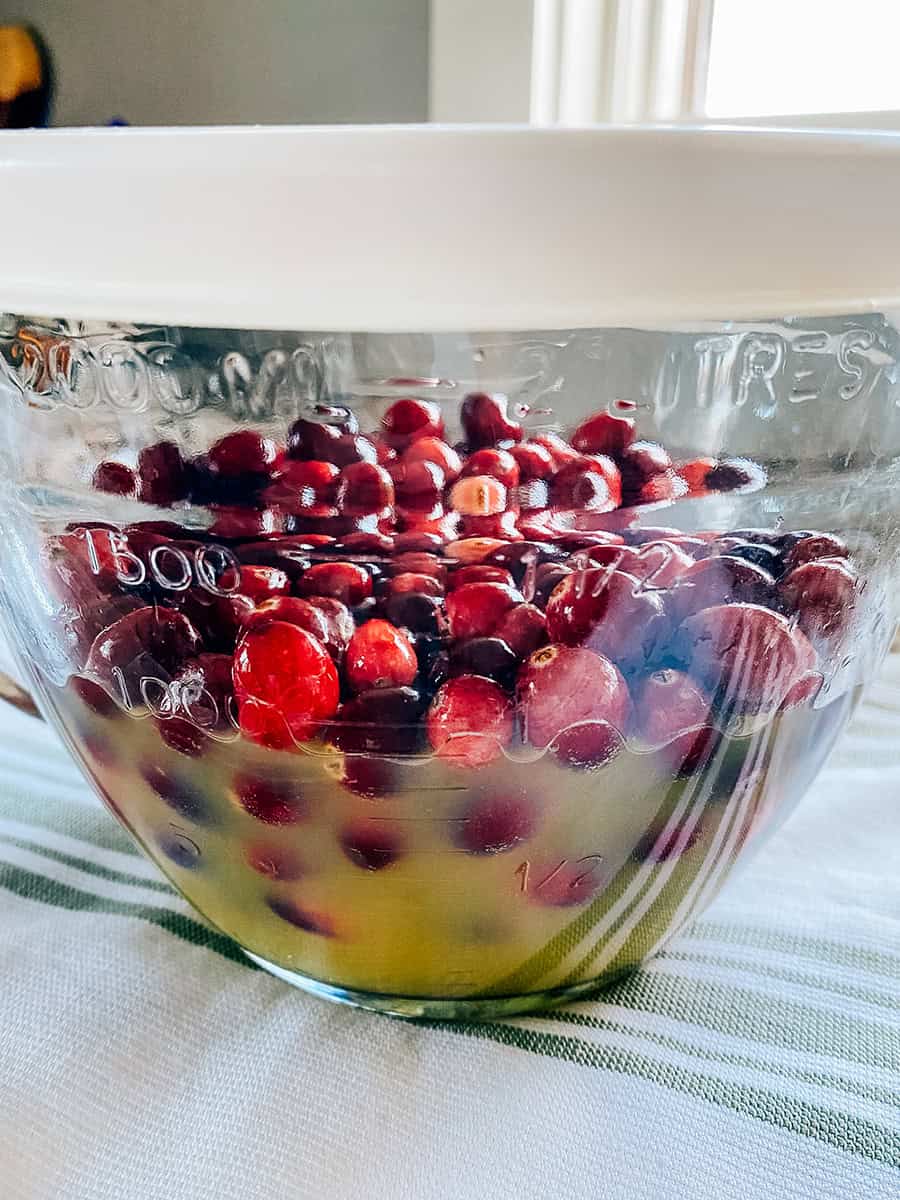 Cranberries in a covered bowl of 7-up and orange juice ready to soak in the refrigerator.