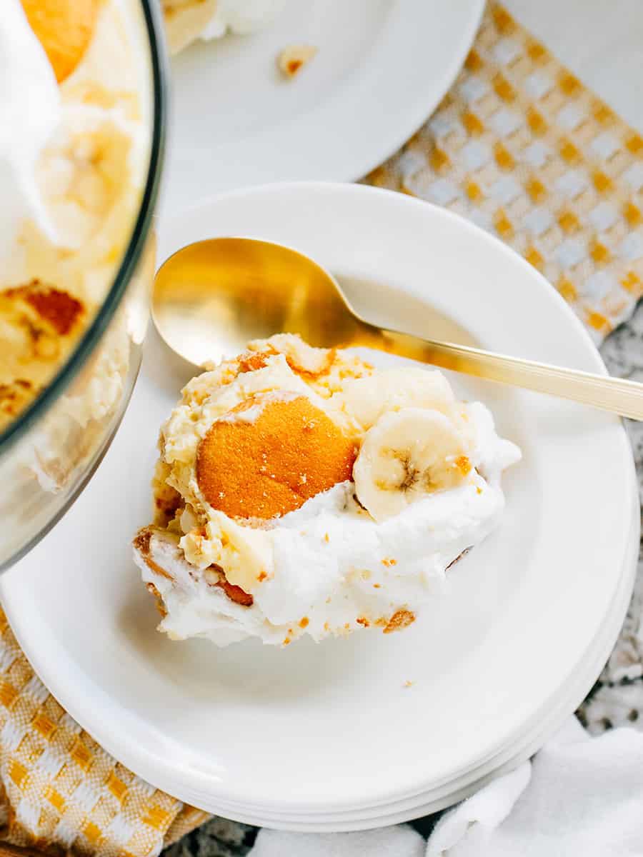 Portion individuelle de pudding à la banane sur une assiette avec une tranche de banane et des gaufrettes Nilla sur le dessus. D'autres assiettes en arrière-plan.