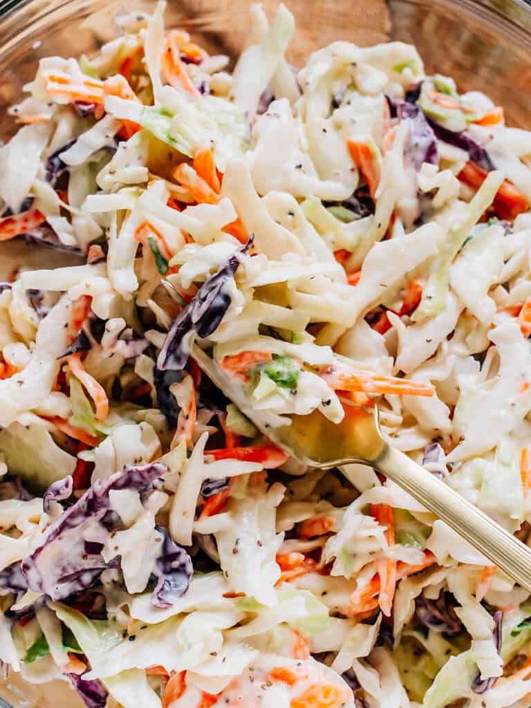 Coleslaw fait avec des carottes râpées, du chou violet et du chou vert sur une fourchette.