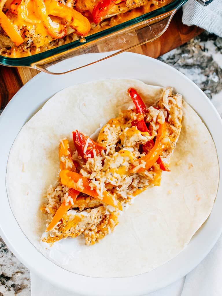 Une tortilla avec de la crème aigre au milieu et ce poulet fajita au four pour un taco de fajitas au poulet simple.