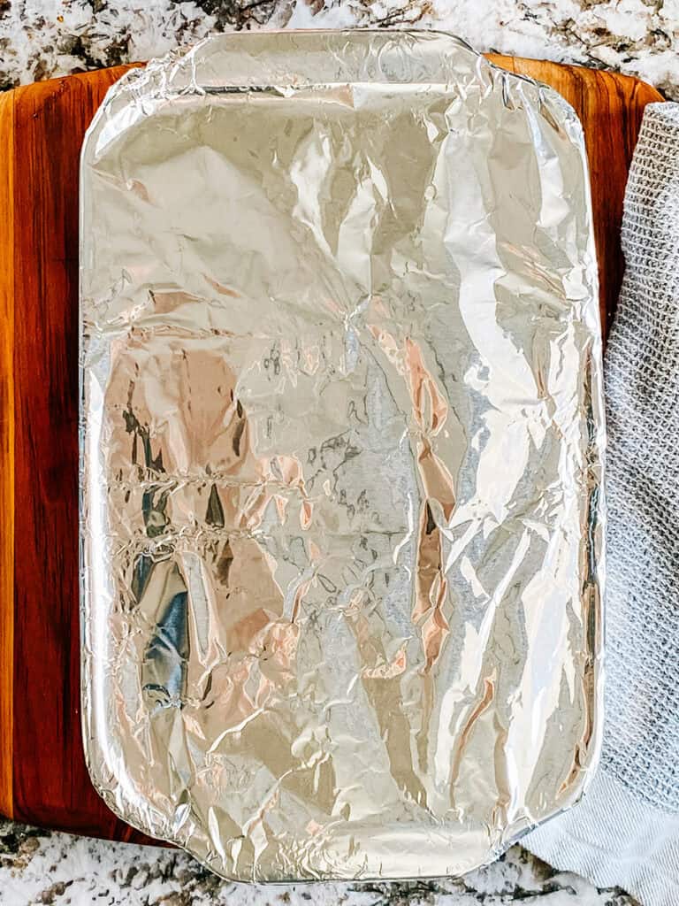 Plat de cuisson de 23x33 cm recouvert hermétiquement de papier aluminium et prêt à être cuit.