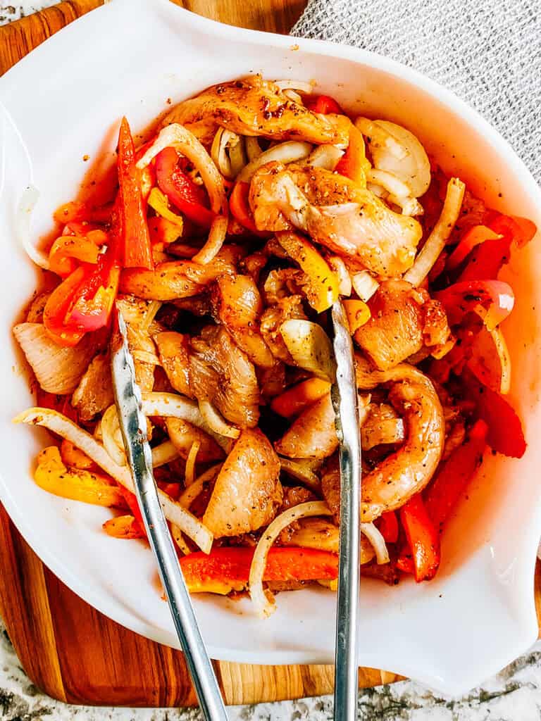 Poitrines de poulet crues, poivrons et oignons recouverts d'un mélange d'huile et d'assaisonnement fajita.
