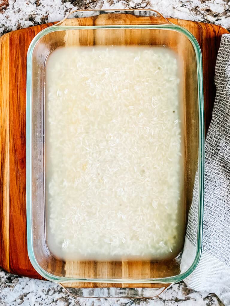 Un plat de cuisson de 23x33 cm avec du bouillon de poulet et du riz non cuit au fond.
