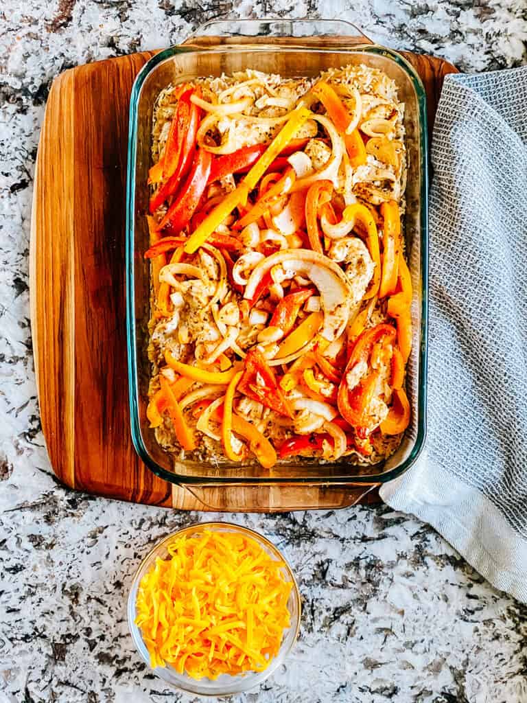 Un plat de 23x33 cm avec des fajitas de poulet cuites et du fromage sur le côté.
