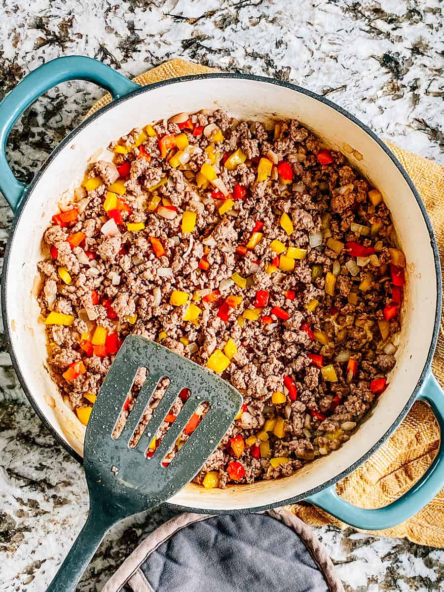 Boeuf haché doré avec poivrons et oignons cuits dans une grande poêle.