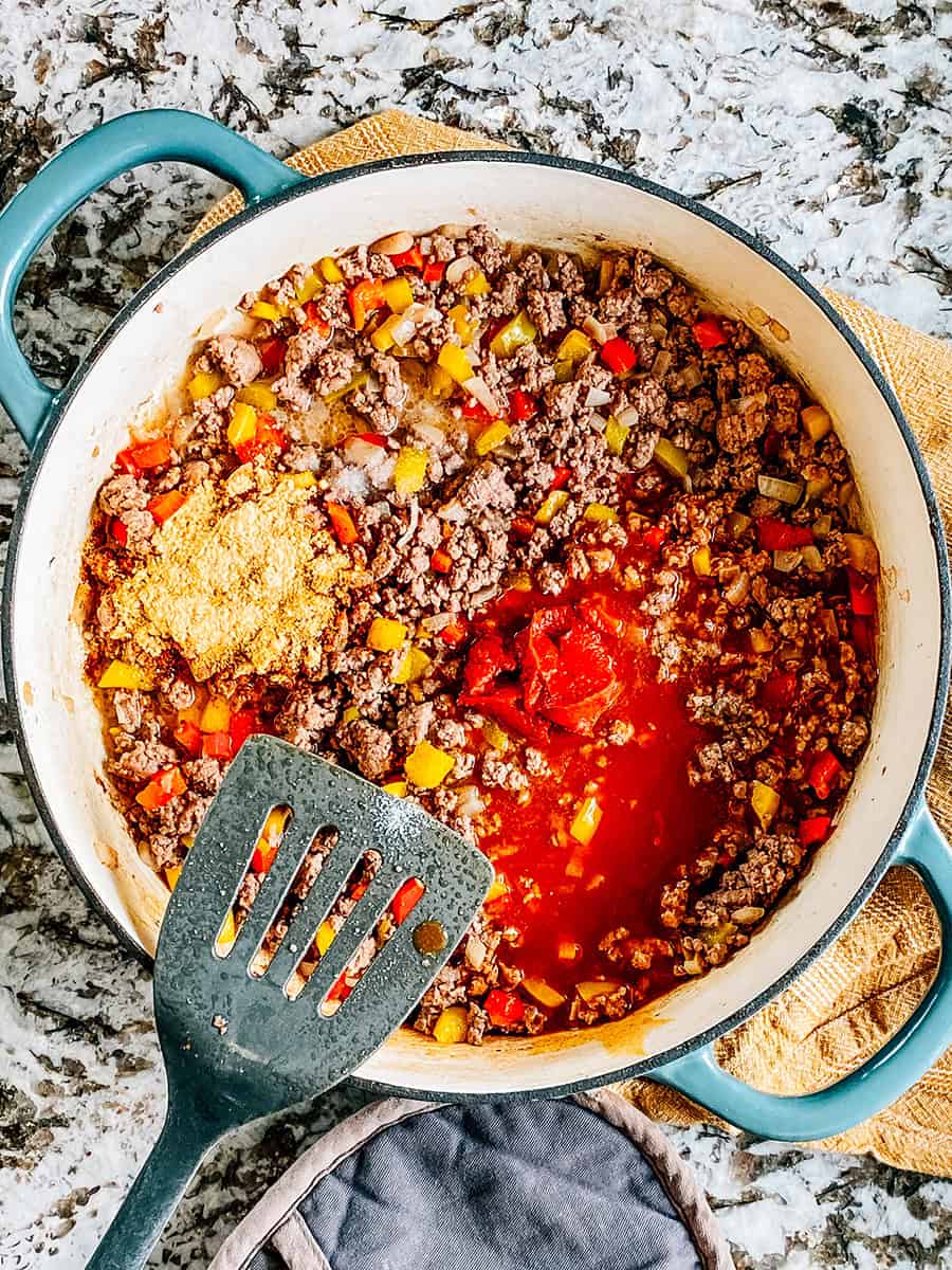 Le boeuf cuit et les poivrons avec le concentré de tomate, le sel, l'assaisonnement à tacos et l'eau au-dessus.