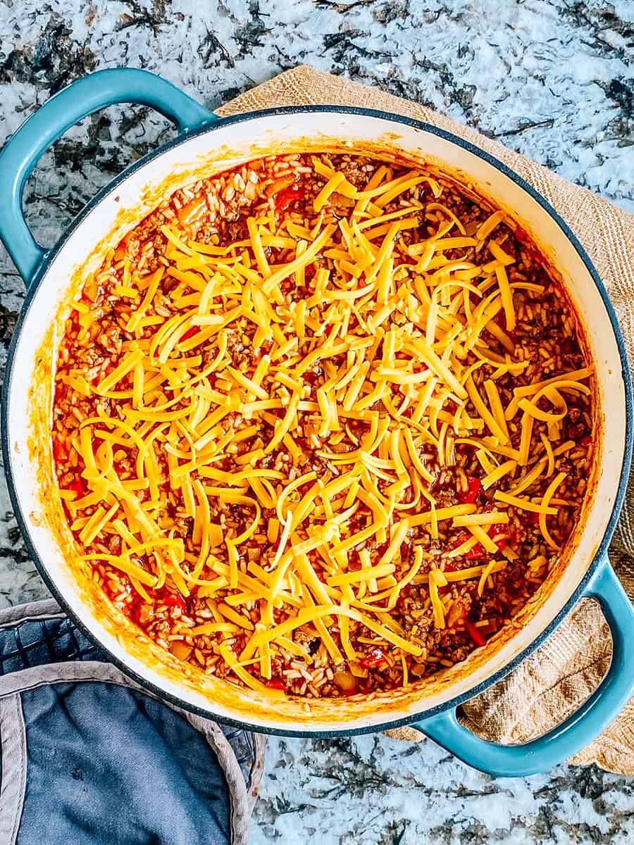 Fromage cheddar râpé sur le dessus de la poêle de boeuf et riz à tacos.
