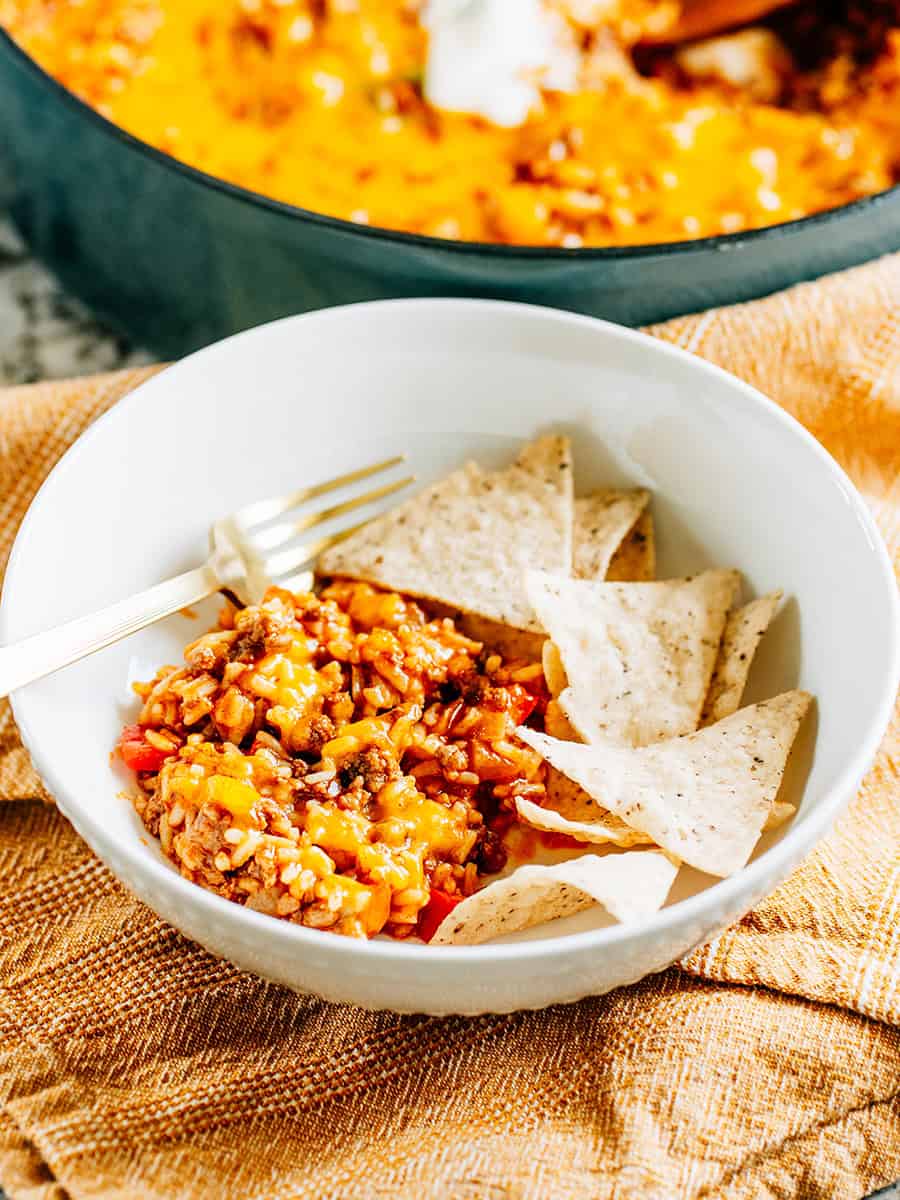 Un bol de poêle de riz aux tacos de boeuf avec des chips de tortilla à côté pour une idée de repas familial facile et amusante !