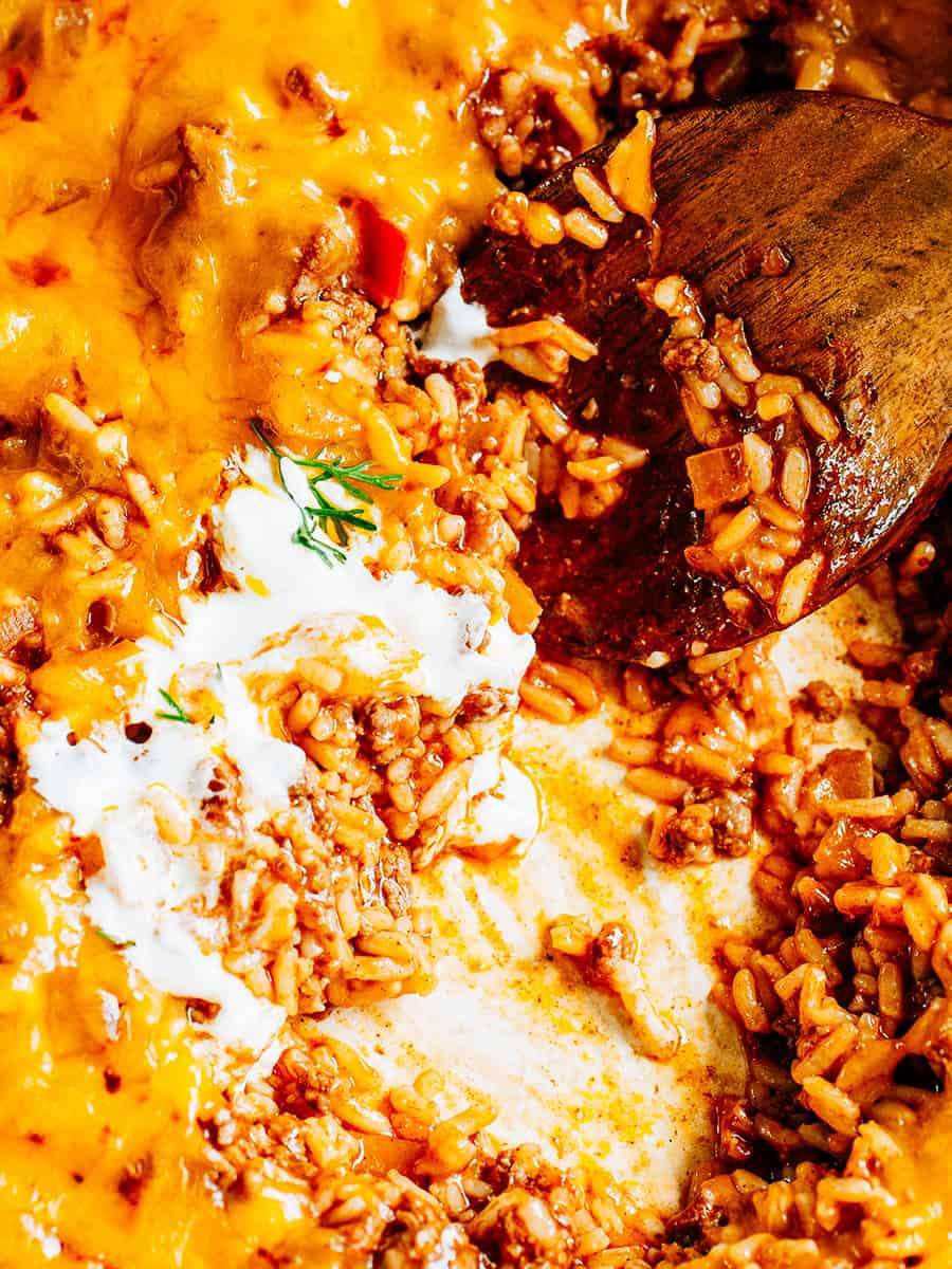 La poêle avec une portion manquante montrant les couches de fromage fondu, de riz et de boeuf haché.