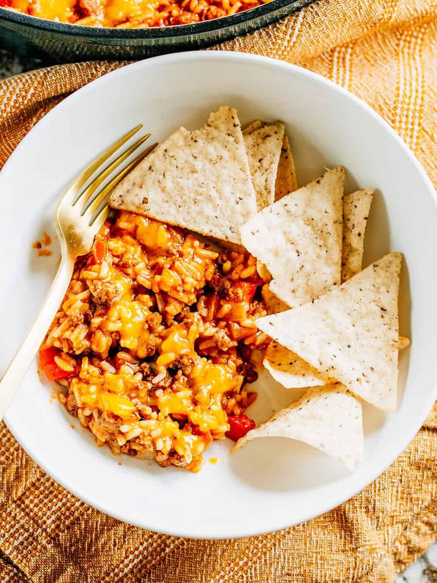 Un bol de poêle de riz aux tacos de boeuf avec des chips de tortilla à côté pour une idée de repas familial facile et amusante !